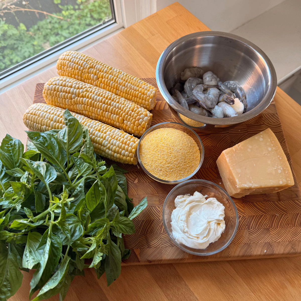 corn, basil, polenta, shrimp, mascarpone and parmesan sit on a cutting board