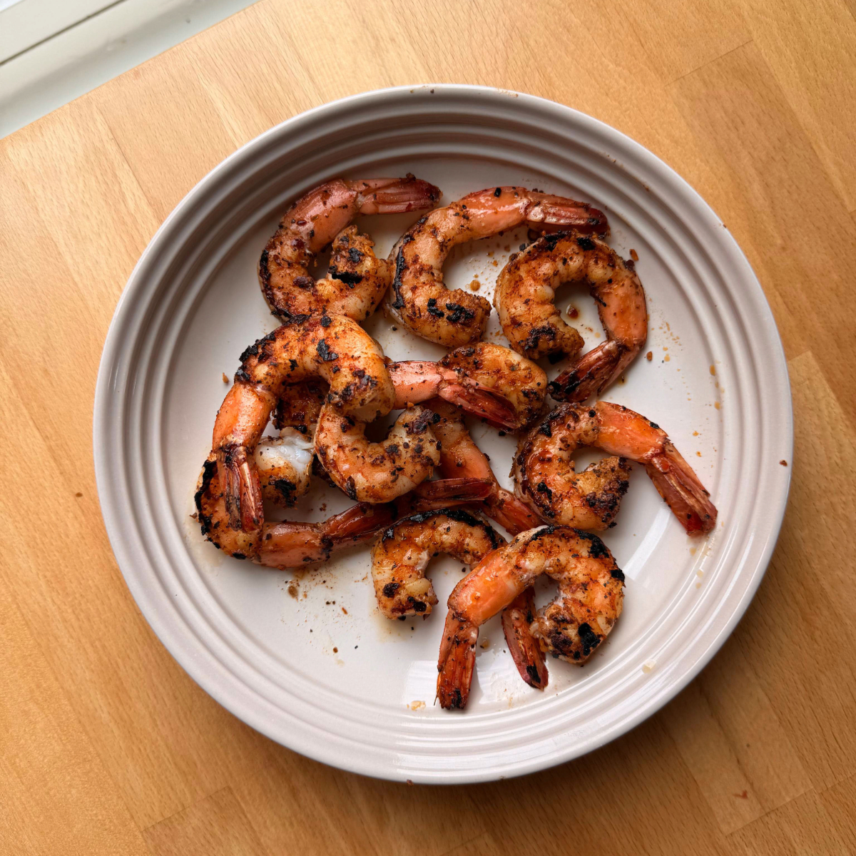 cooked jumbo shrimp with Old Bay seasoning in a shallow bowl on a wooden counter