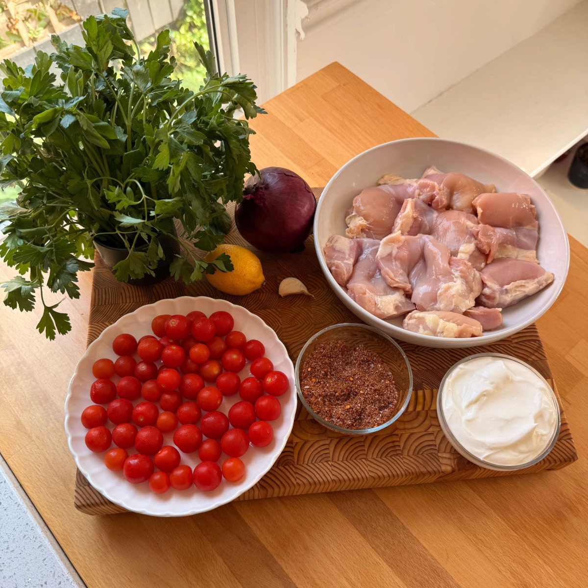 Ingredients for chicken shawarma sheet pan dinner are laid out on a wooden cutting board