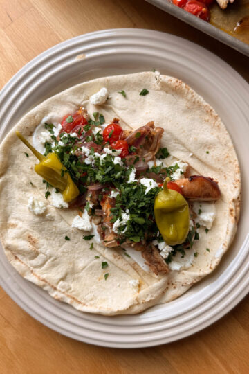 sheet pan chicken shawarma on a pita with feta, garlic sauce, parsley and peppers