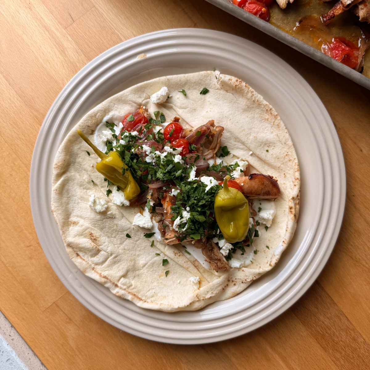 sheet pan chicken shawarma on a pita with feta, garlic sauce, parsley and peppers