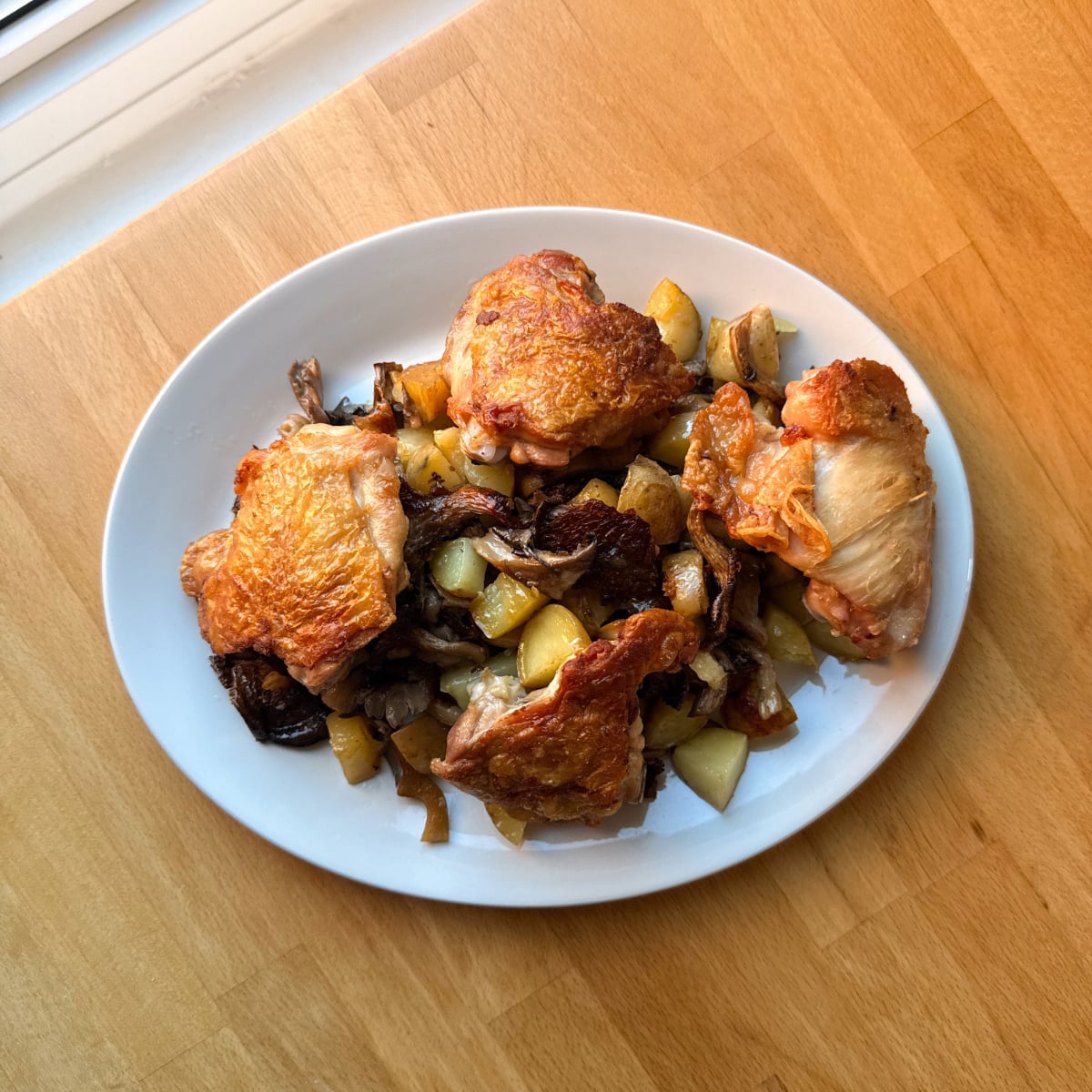 crispy skin chicken thighs on a bed of roasted potatoes and caramelized mushrooms before adding pepper sauce