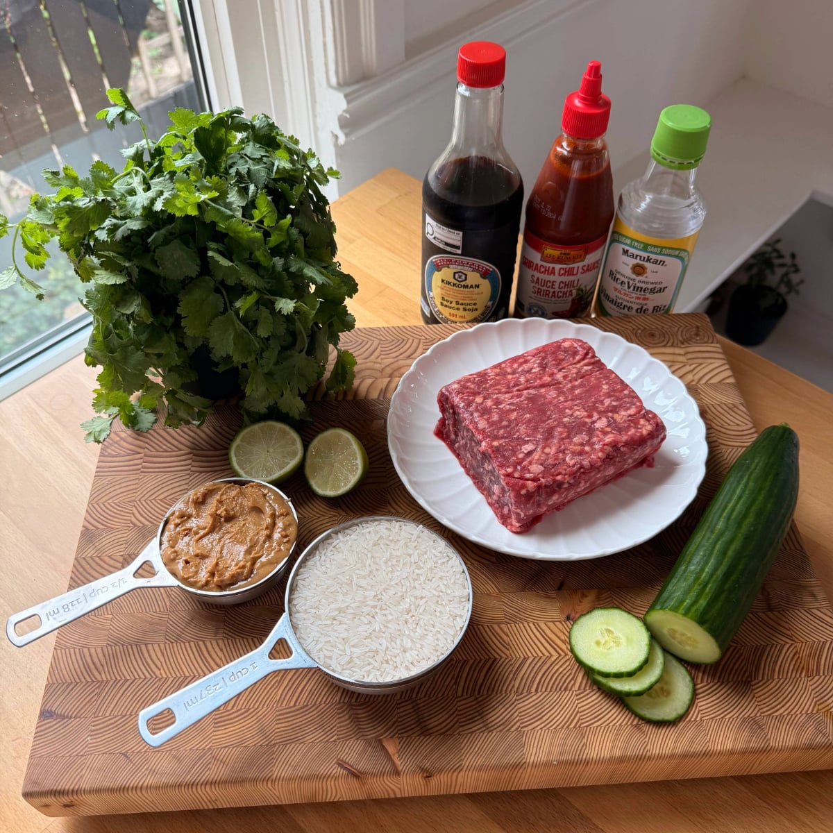 ingredients to make peanut soy ground beef bowls laid out on a wooden cutting board