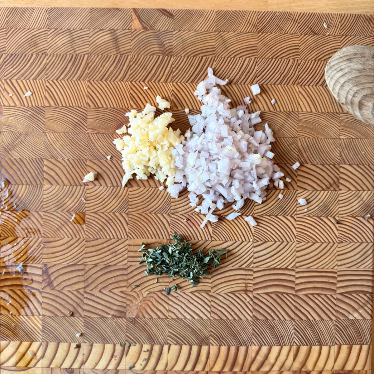 diced shallots, garlic and thyme leaves on a cutting board prepped for au poivre sauce