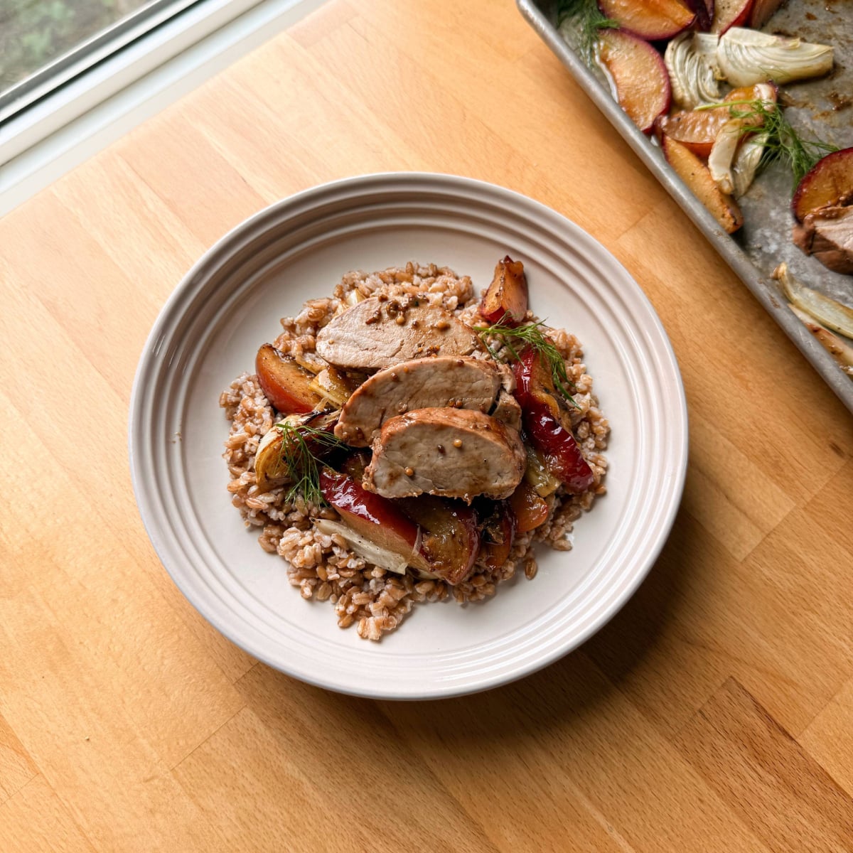 Oven roasted pork tenderloin served with jammy plums and caramelized fennel atop butter-y farro